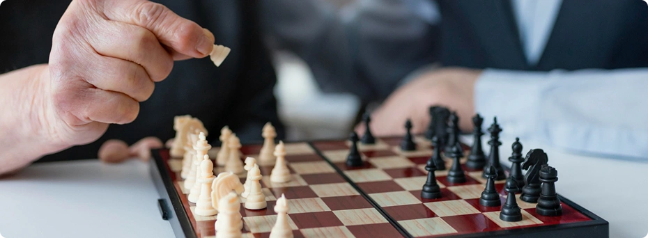 Close-up van een persoon die een schaakstuk verplaatst op een schaakbord tijdens een strategisch bordspel.