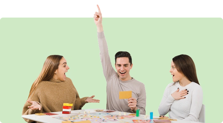 Drie vrienden spelen een bordspel aan een tafel, terwijl één speler enthousiast zijn hand opsteekt nadat hij een ronde heeft gewonnen.